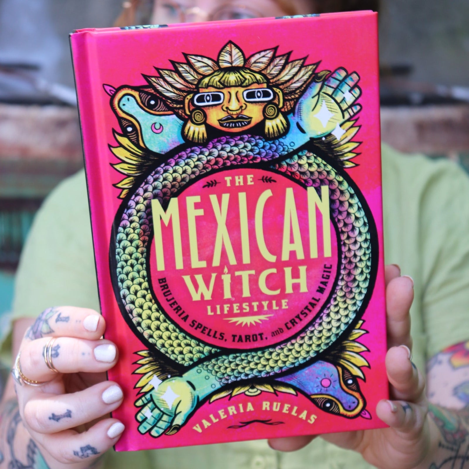 A woman holding the Mexican Witch Lifestyle Hardcover Book.