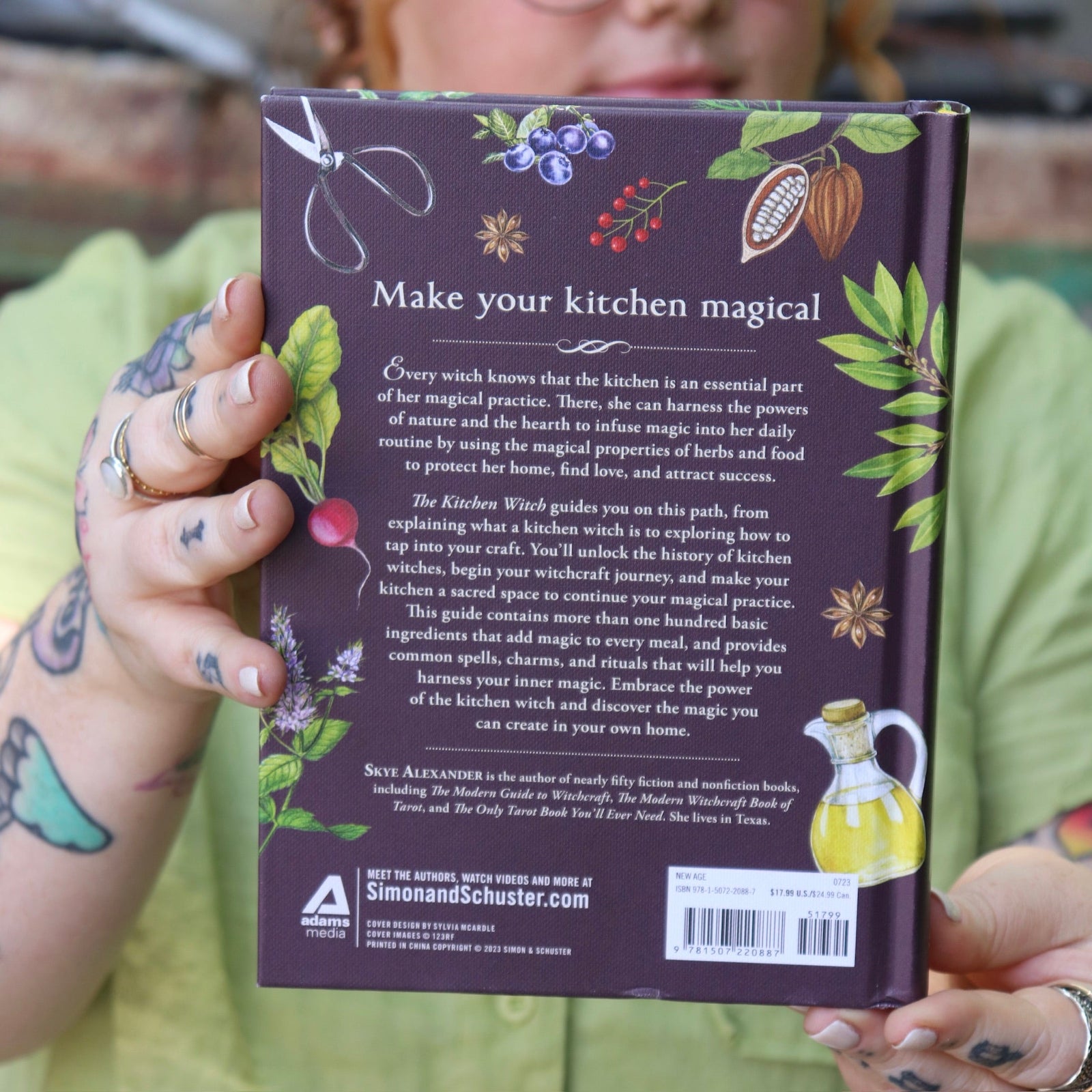 A woman holding the The Kitchen Witch Hardcover Book.