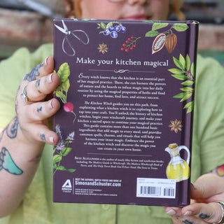 A woman holding the The Kitchen Witch Hardcover Book.