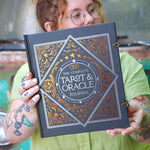 A woman holding the Complete Tarot & Oracle Journal Hardcover Book.
