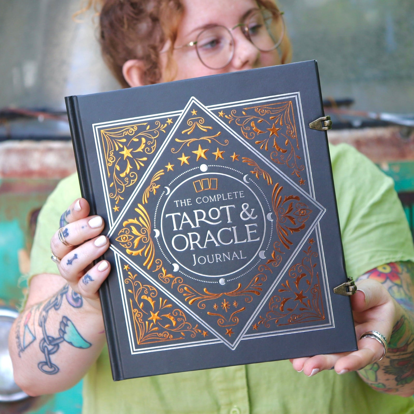 A woman holding the Complete Tarot & Oracle Journal Hardcover Book.