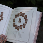 A woman holding the Complete Tarot & Oracle Journal Hardcover Book open to show off the pages.