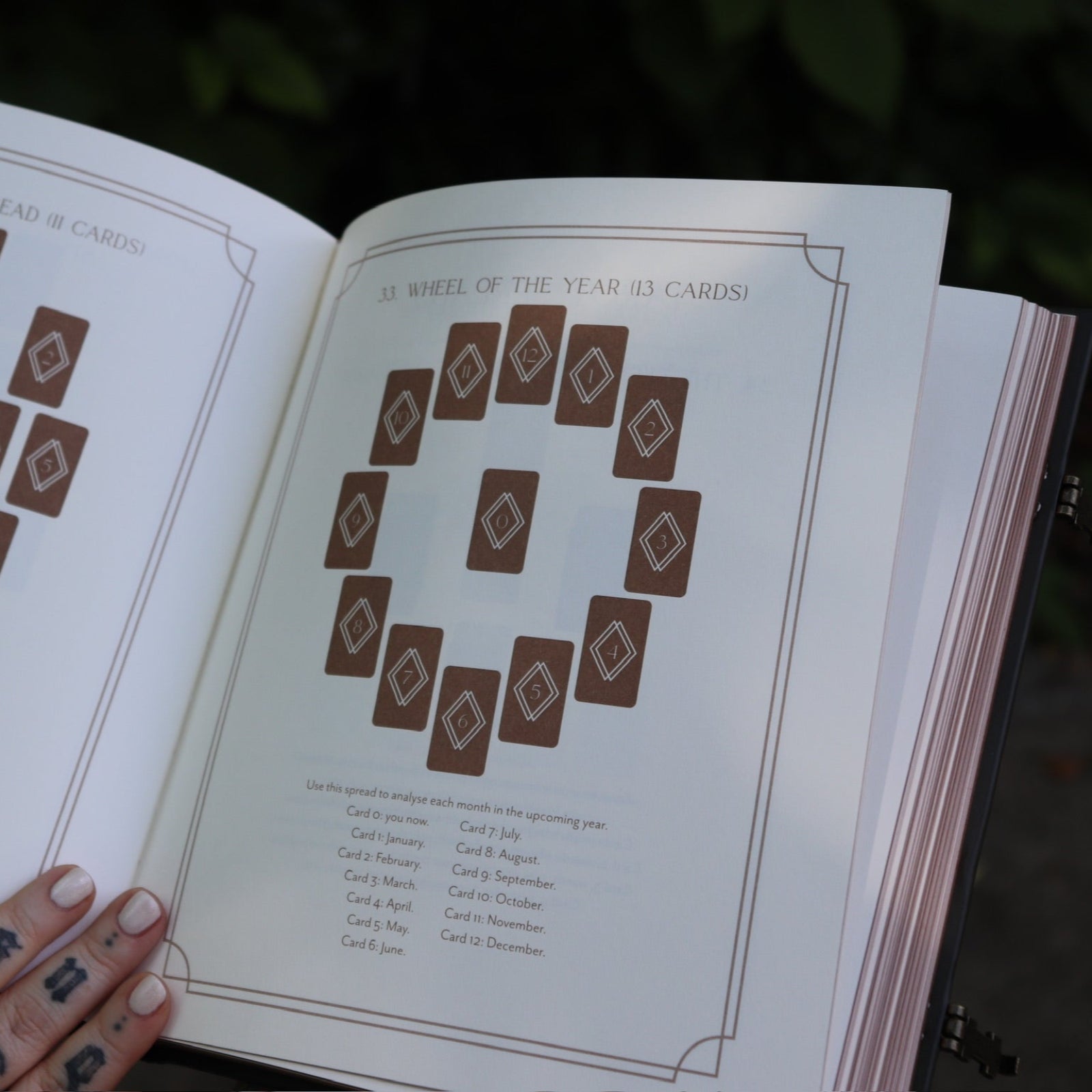 A woman holding the Complete Tarot & Oracle Journal Hardcover Book open to show off the pages.