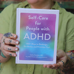 A woman holding the Self-Care for People with ADHD Hardcover Book.