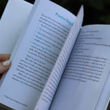A woman holding the Self-Care for People with ADHD Hardcover Book open to show off its pages.