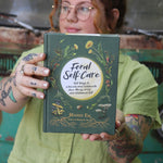 A woman holding the Feral Self-Care Hardcover Book.