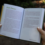 A woman holding the Feral Self-Care Hardcover Book open to show off its pages.