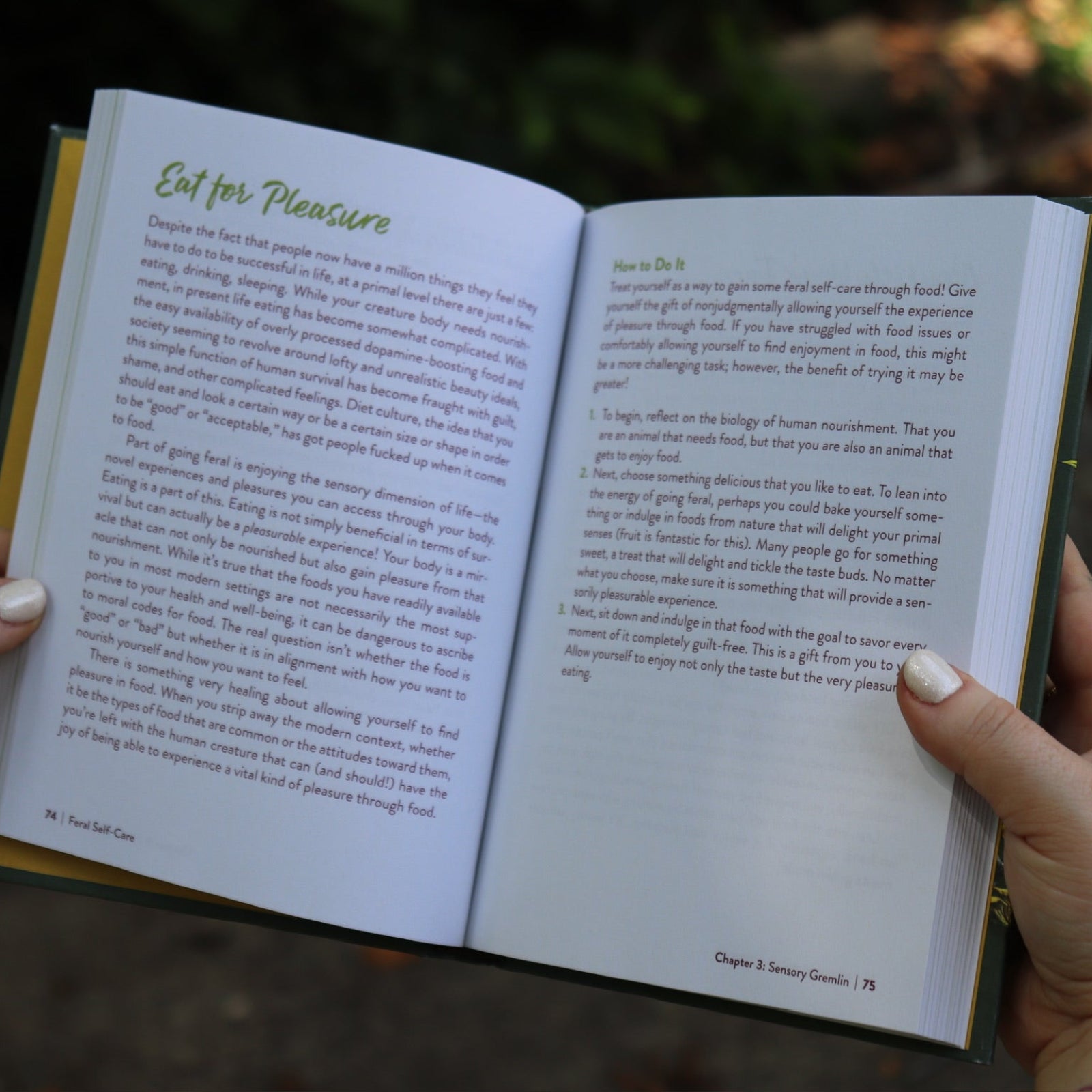 A woman holding the Feral Self-Care Hardcover Book open to show off its pages.