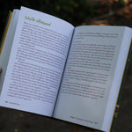 A woman holding the Feral Self-Care Hardcover Book open to show off its pages.