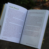 A woman holding the Feral Self-Care Hardcover Book open to show off its pages.