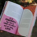 A woman holding the Women Living Deliciously Hardcover Book open to show off its pages.