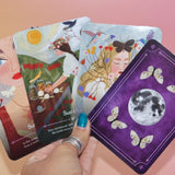 Someone holding four cards from the Seasons of the Witch - Litha Oracle Card Deck.