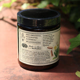 The side of the Liver Vitality Greens - 4oz Powder Daily Cleanser on a red surface with greenery to its right.