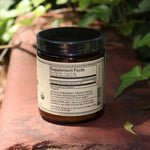 The back of the Moringa Super-Tonic - 4.5oz Powder Energy Booster on red concrete next to greenery.