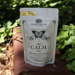 The Calm + Stress Relief Tonic Tea on a rusty red surface next to ivy.