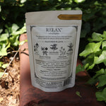 The back of the Calm + Stress Relief Tonic Tea on a rusty red surface next to ivy.