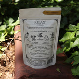 The back of the Calm + Stress Relief Tonic Tea on a rusty red surface next to ivy.