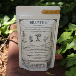 The back of the Breathe - Organic Lung Tonic Tea on a rusty red surface next to ivy.