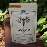 The Womb Tea - Nourish + Empower Tonic Tea red surface next to ivy.