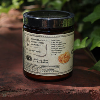 The side of the Cordyceps Energy Super Tonic Mushroom Powder on a red surface next to greenery.