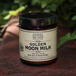 The Golden Moon Milk - 5oz Blue Lotus Vanilla Powder on a red surface next to ivy.