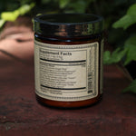 The back of the Golden Moon Milk - 5oz Blue Lotus Vanilla Powder on a red surface next to ivy.