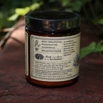 The side of the Golden Moon Milk - 5oz Blue Lotus Vanilla Powder on a red surface next to ivy.