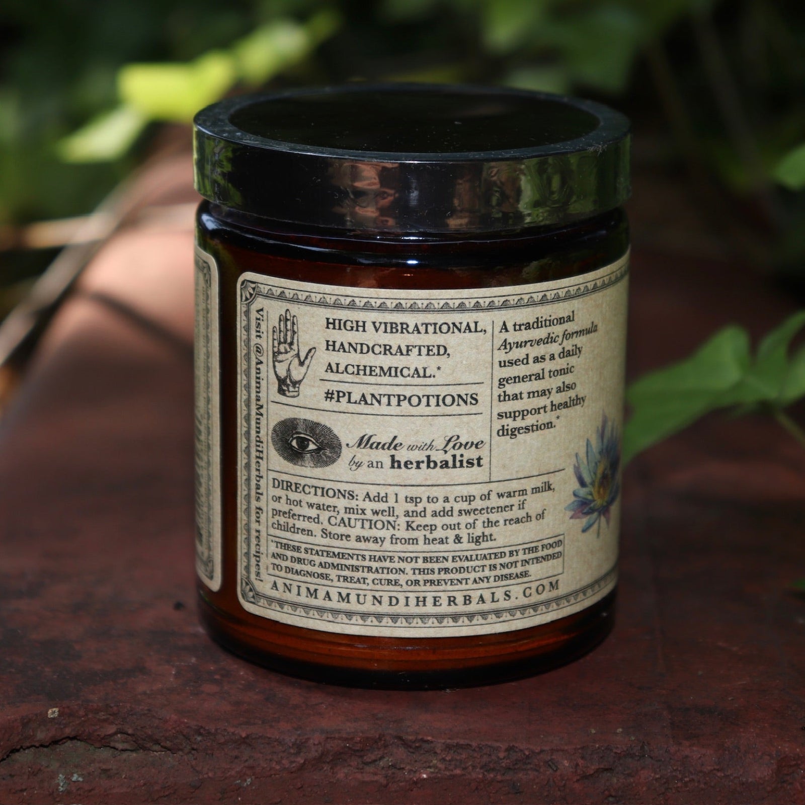 The side of the Golden Moon Milk - 5oz Blue Lotus Vanilla Powder on a red surface next to ivy.