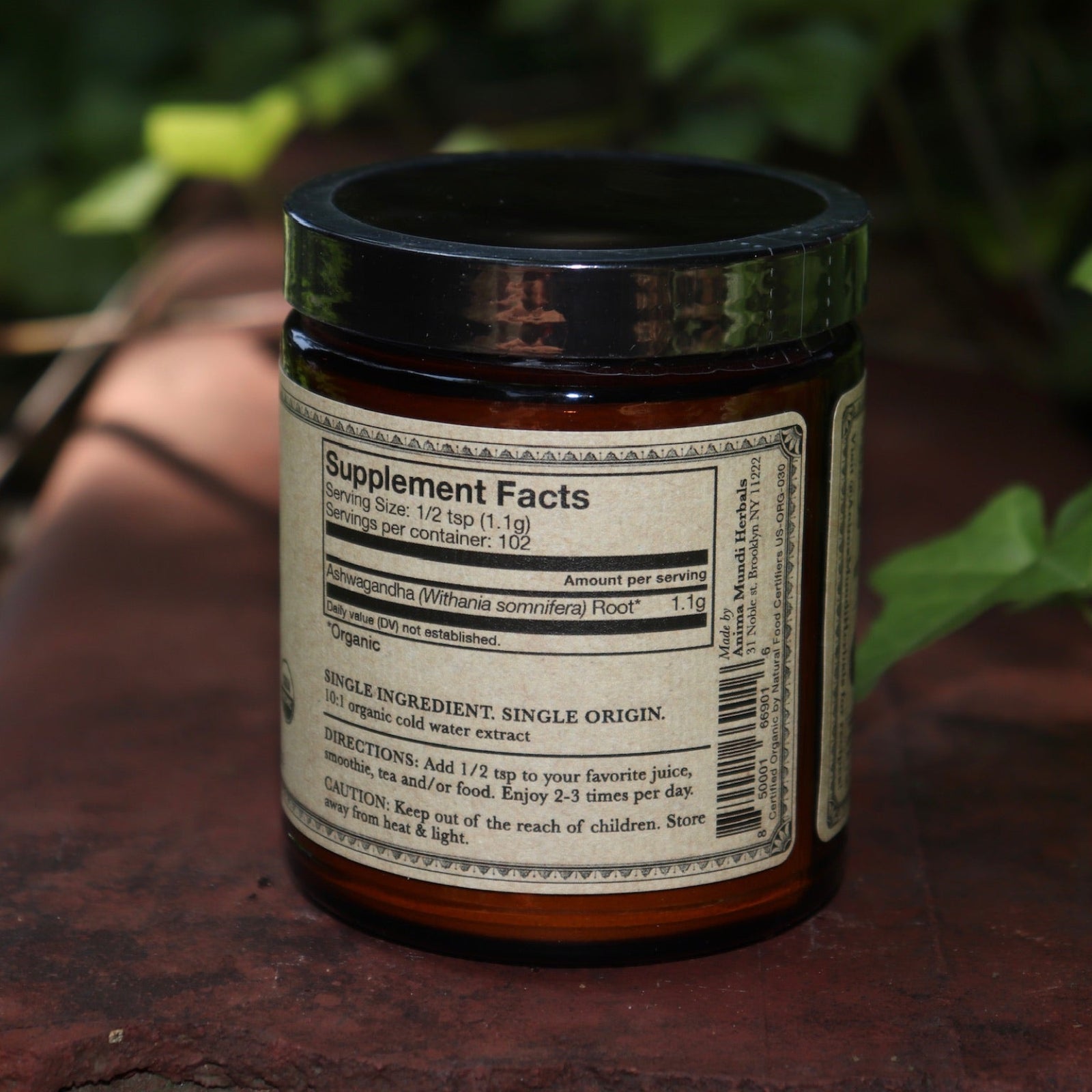 The Ashwagandha Nature's Chill Pill 4 oz Powder on a rusty red surface surrounded by ivy.