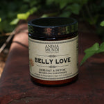 The Belly Love - Metabolism Harmonizer 4.5 oz Powder on a rusty red surface surrounded by green ivy.