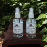 The The Rose Water Beauty Mist - Soothing Face Toner next to a palo santo pray on a rusty red surface next to ivy.
