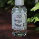 The side of the Palo Santo Protection Mist - Auric Purification on a rusty red surface next to ivy.