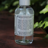 The back of the Palo Santo Protection Mist - Auric Purification on a rusty red surface next to ivy.