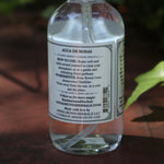 The back of the Rose Water Beauty Mist - Soothing Face Toner on a rusty red surface next to ivy.
