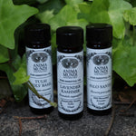 All the Anima Mundi Apothecary essential oils (Tulsi Holy Basil, Lavender Kashmir, and Palo Santo) on a concrete surface in front of a patch of ivy.