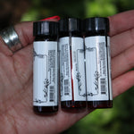 Someone holding all the Anima Mundi Apothecary essential oils (Tulsi Holy Basil, Lavender Kashmir, and Palo Santo).