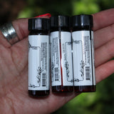 Someone holding all the Anima Mundi Apothecary essential oils (Tulsi Holy Basil, Lavender Kashmir, and Palo Santo).