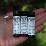 Someone holding all the Anima Mundi Apothecary essential oils (Tulsi Holy Basil, Lavender Kashmir, and Palo Santo).
