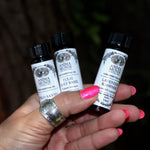 Someone holding all the Anima Mundi Apothecary essential oils (Tulsi Holy Basil, Lavender Kashmir, and Palo Santo).