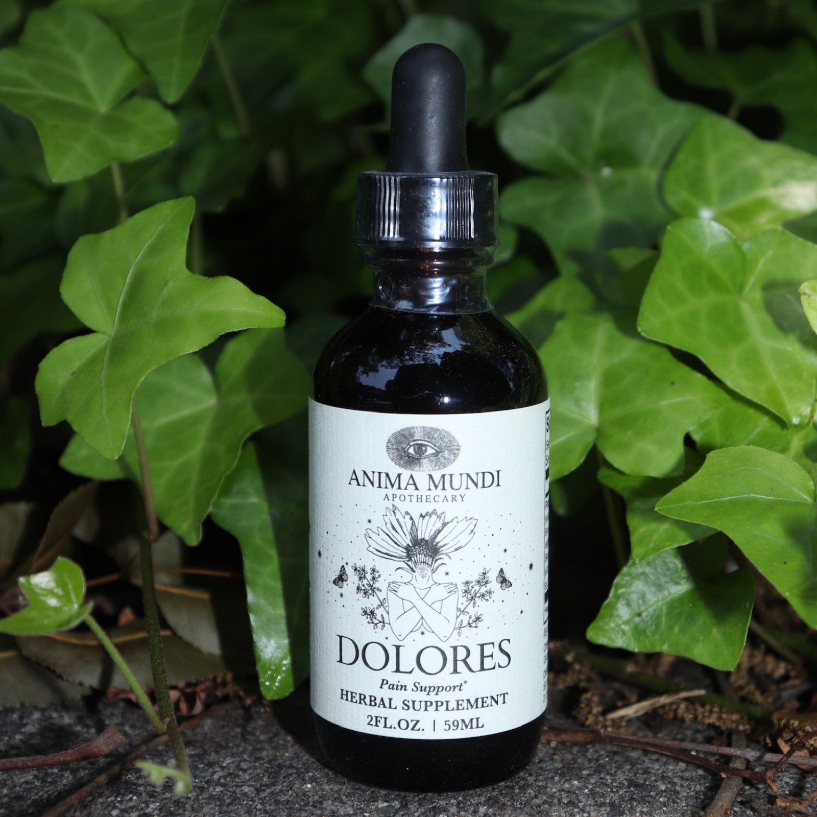 The Dolores - Muscular Comfort + Nerve Support Tonic on a concrete surface in front of an ivy patch.