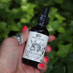 Someone holding the Cerebrum - Nootropic + Cognitive Support Tonic in front of a patch of ivy.