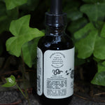 The side of the Adaptogenic 7 Mushroom Vitality + Immune Support Tonic on a concrete surface in front of ivy.