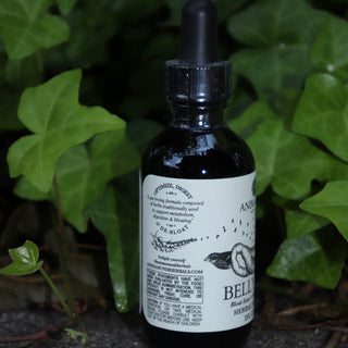 The Belly Love - 2oz Metabolism + Digestive Support Tonic in front of ivy.