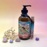 The The Vanilla Effect Body Cream Moisturizer surrounded by crystals and a dried flower on a light pink background.