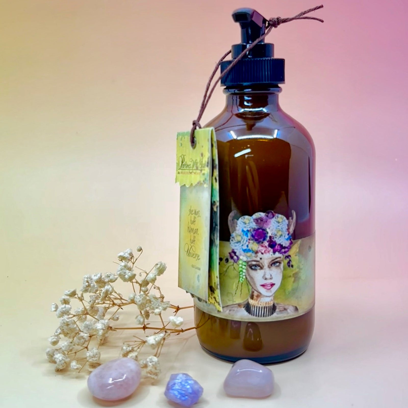 The Lemon Freckle Body Cream Moisturizer surrounded by crystals and a dried flower on a light pink background.