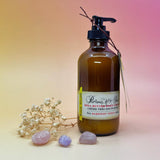 The Lemon Freckle Body Cream Moisturizer surrounded by crystals and a dried flower on a light pink background.