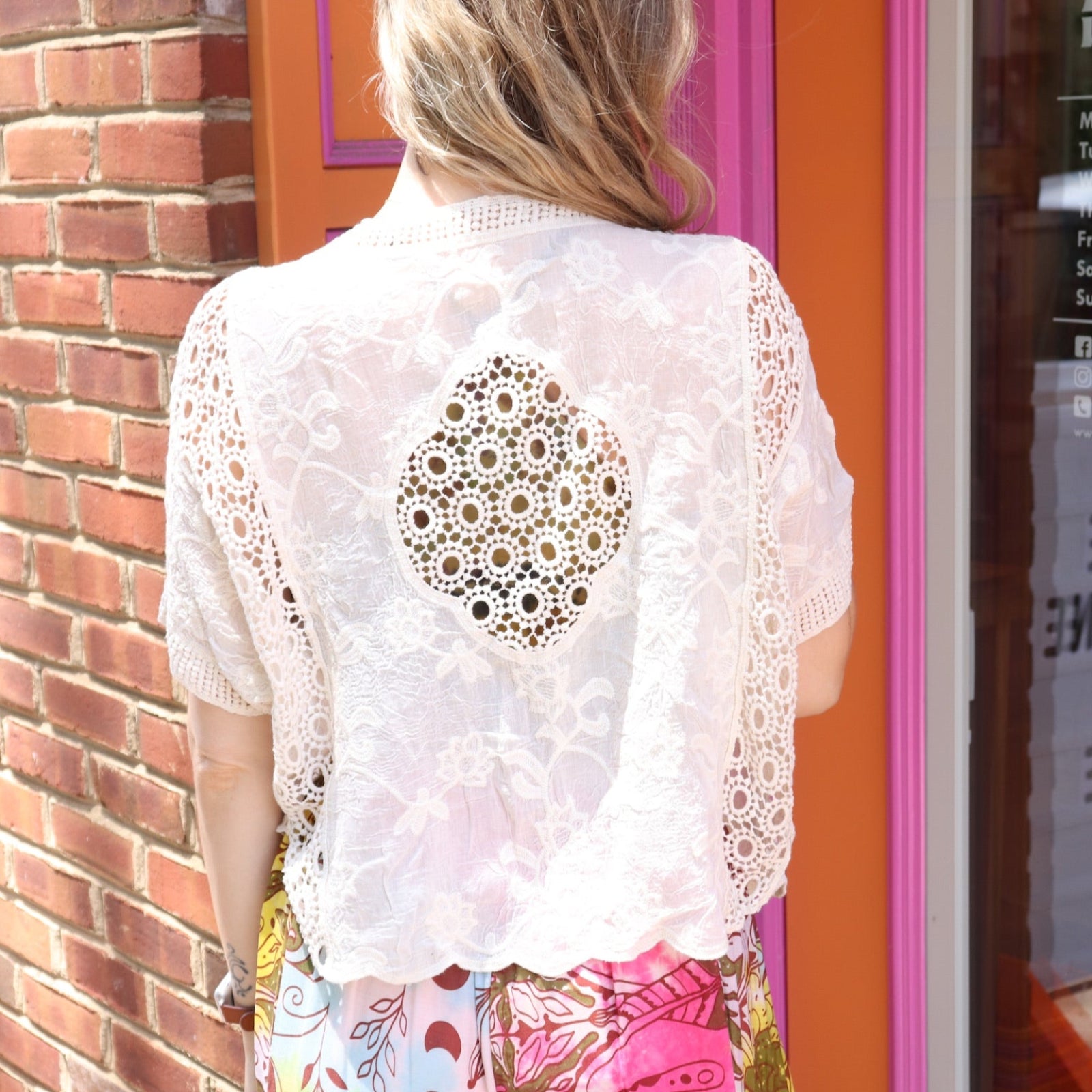 A woman wearing the beige Lace Open Front Cardigan with Batwing Sleeves with tie-dye bottoms and top.