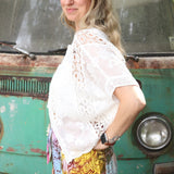 A woman wearing the white Lace Open Front Cardigan with Batwing Sleeves with tie-dye bottoms and crochet top.