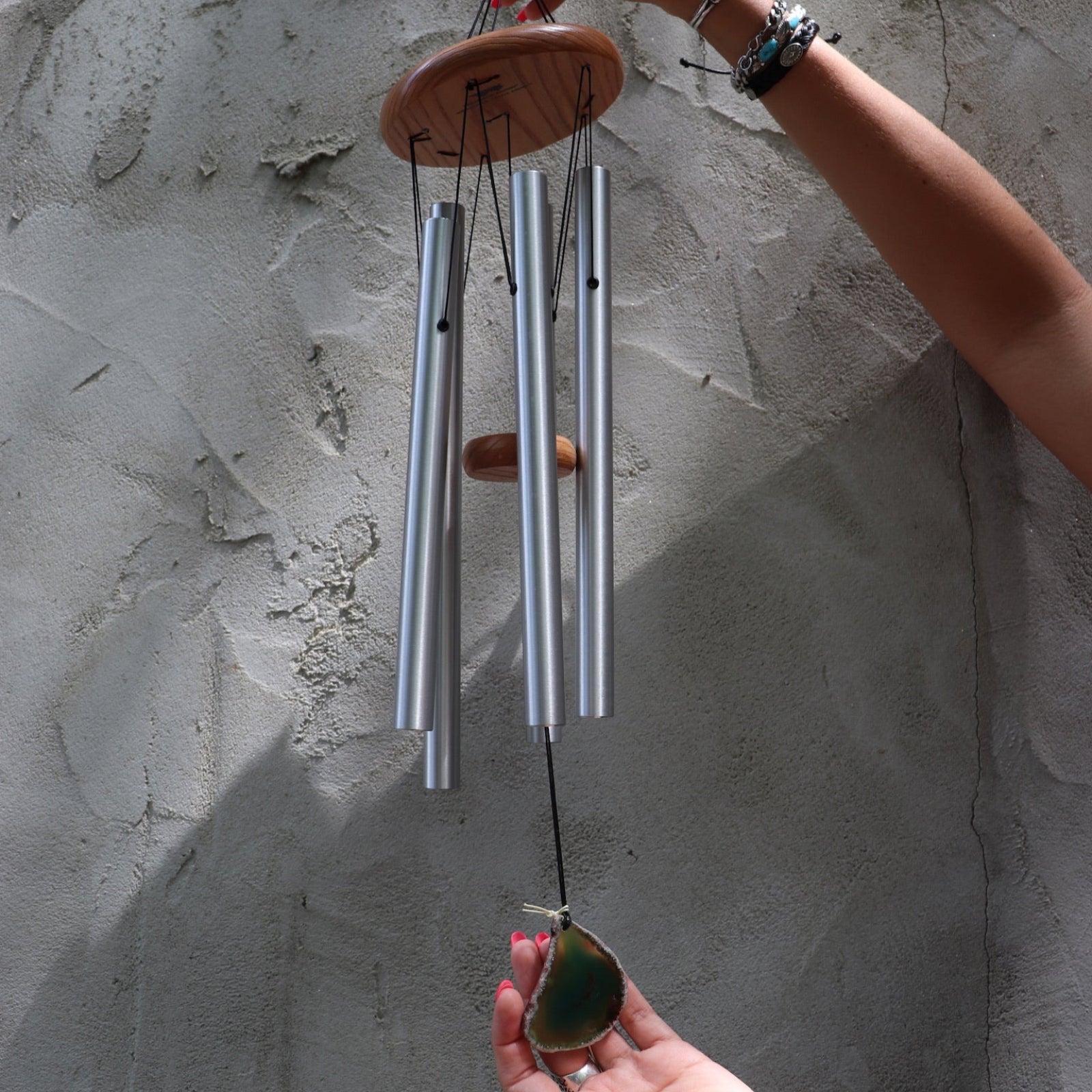 Someone holding the Woodstock Agate Celtic Chime in front of a concrete wall.