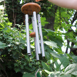 Someone holding the Woodstock Agate Celtic Chime in front of bushes.